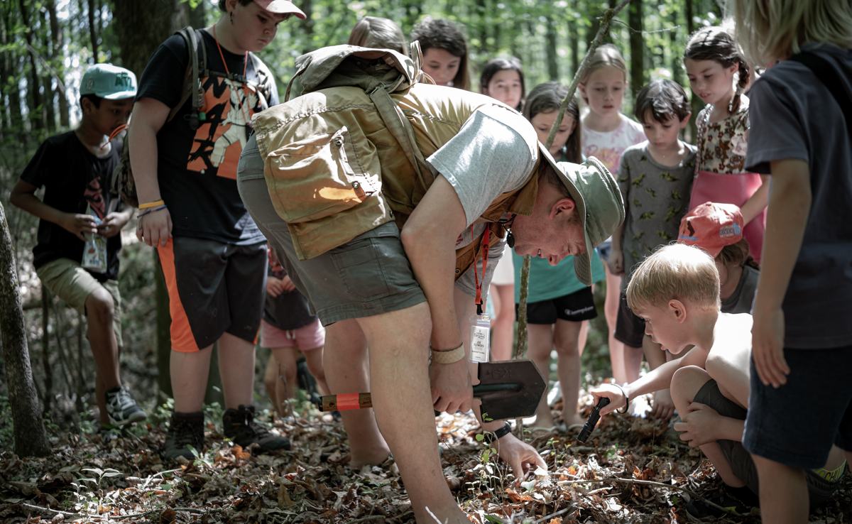 Kids exploring the forest floor with an instructor at a past Georgia Bushcraft event