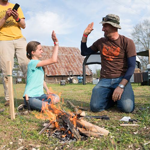 A girl and instructor celebrating her fire at a past Gathering